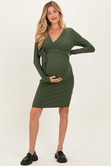 woman wearing a dark green long sleeve maternity dress with a tie waist and visible baby bump