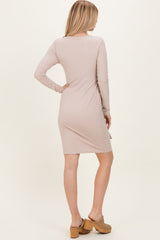 woman wearing a light pink long sleeve ribbed dress with a fitted silhouette and knee-length hemline