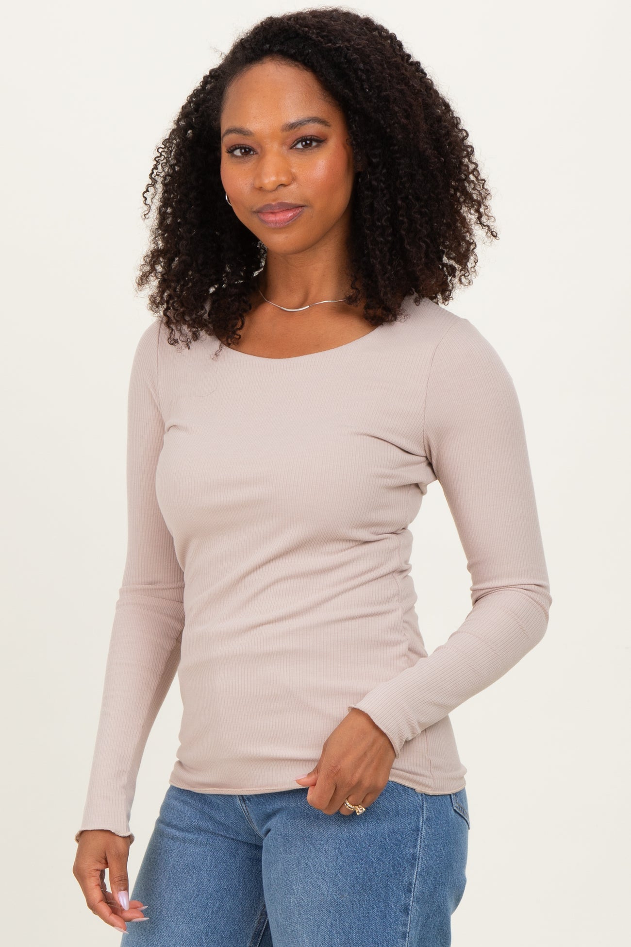 woman wearing a light taupe ribbed long sleeve top and blue jeans