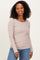 woman wearing a beige long sleeve ribbed top with a scoop neckline and smiling