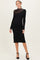 woman wearing a black ribbed maternity dress with a sheer mesh detail at the neckline and long sleeves, showing a baby bump