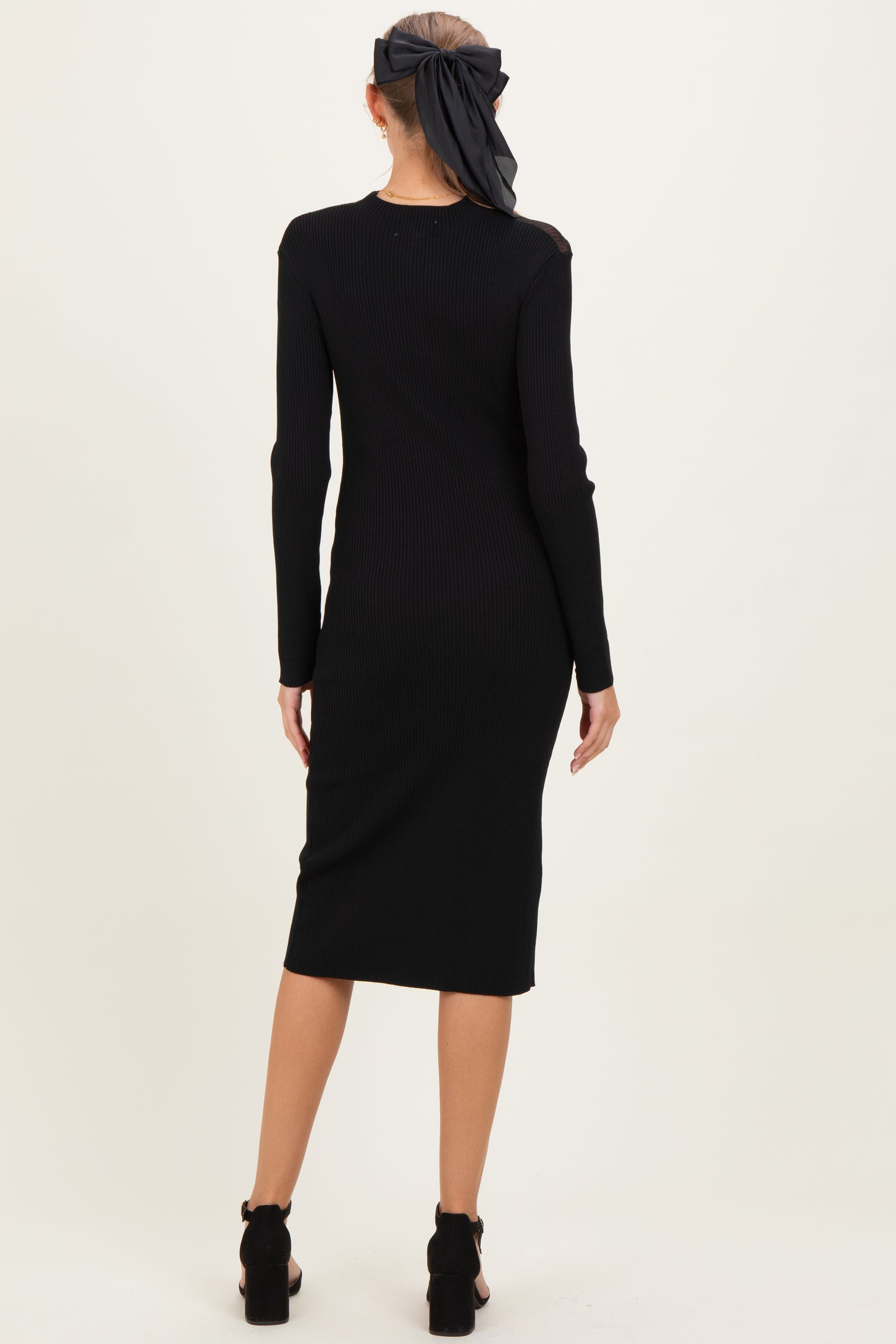 woman wearing a black ribbed maternity dress with long sleeves and a fitted midi length