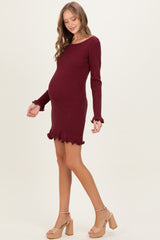 woman wearing a burgundy long sleeve maternity dress with ruffle hem and a visible baby bump