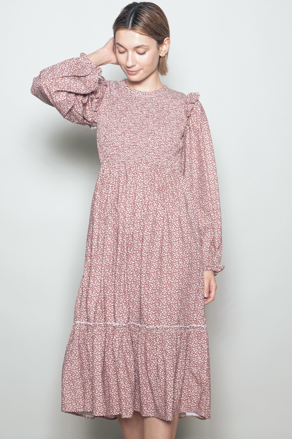 woman wearing a pink floral print long sleeve dress with ruffled details and a tiered hemline