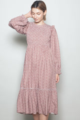 woman wearing a pink floral print long sleeve dress with ruffled details and a tiered hemline