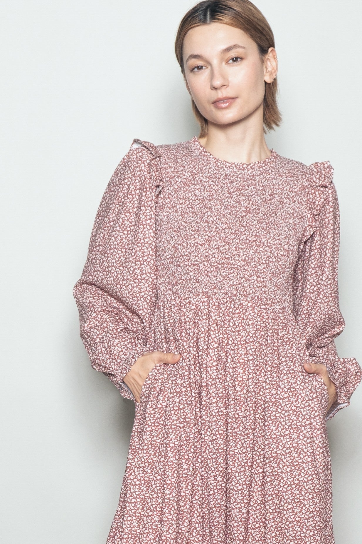 woman wearing a pink floral long sleeve dress with puffed sleeves and pockets
