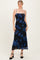 woman wearing a black floral midi dress with blue flowers and spaghetti straps, posing confidently