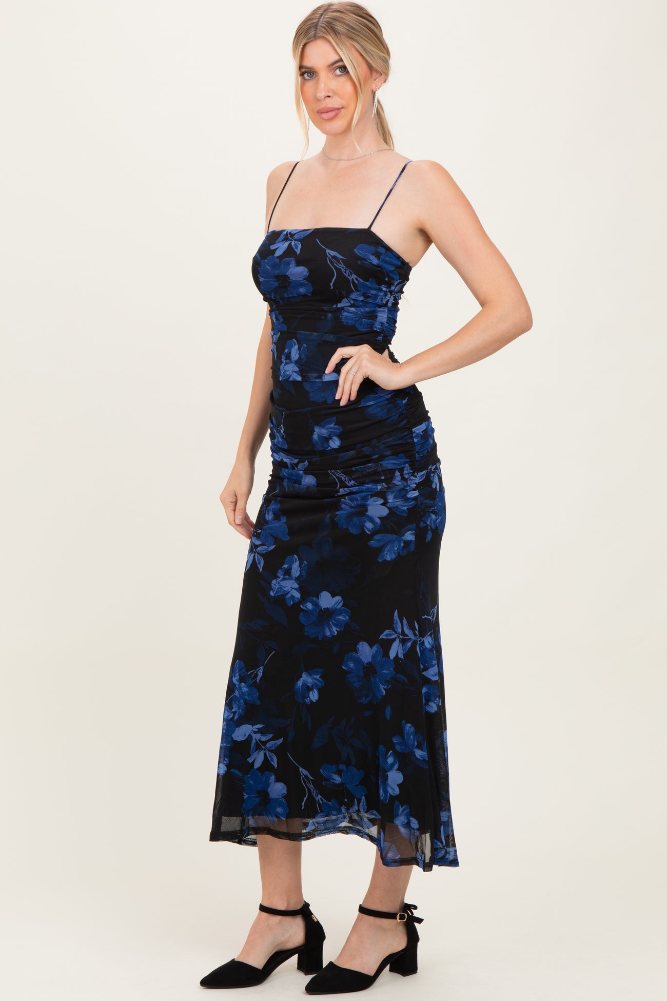 woman wearing a black floral midi dress with blue flowers and adjustable spaghetti straps