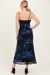 woman wearing a black floral maxi dress with blue flowers and ruching details, showing the back view