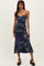 woman wearing a strapless navy floral midi dress with ruching and a flared hem, standing in black heels