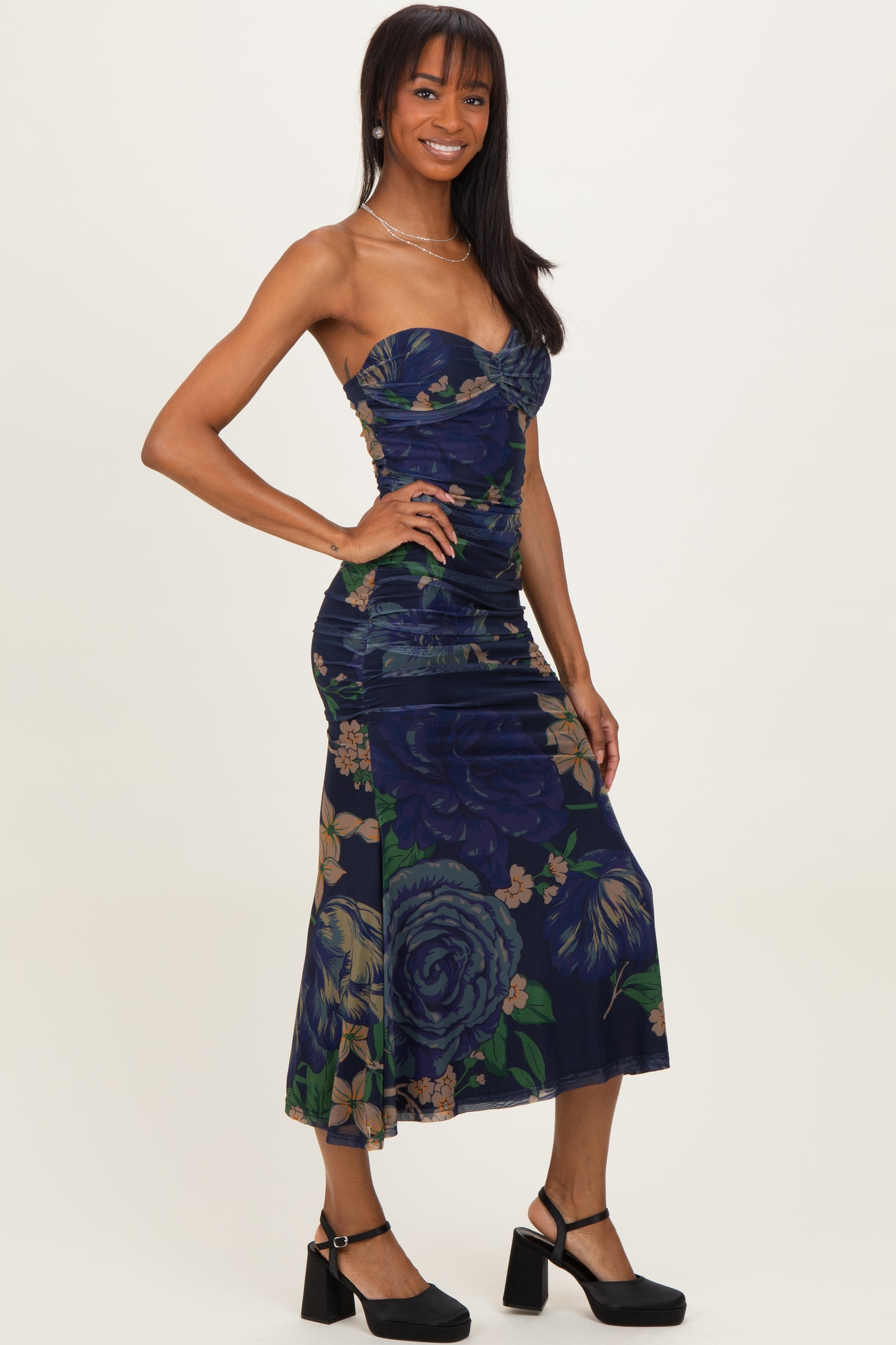 woman wearing a navy floral print midi dress with a ruched bodice and a fitted silhouette