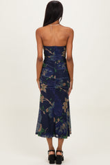 woman wearing a dark floral strapless midi dress with ruching and a flowing skirt, viewed from the back