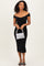 woman wearing a black off-the-shoulder fitted dress with textured details, holding a silver striped handbag