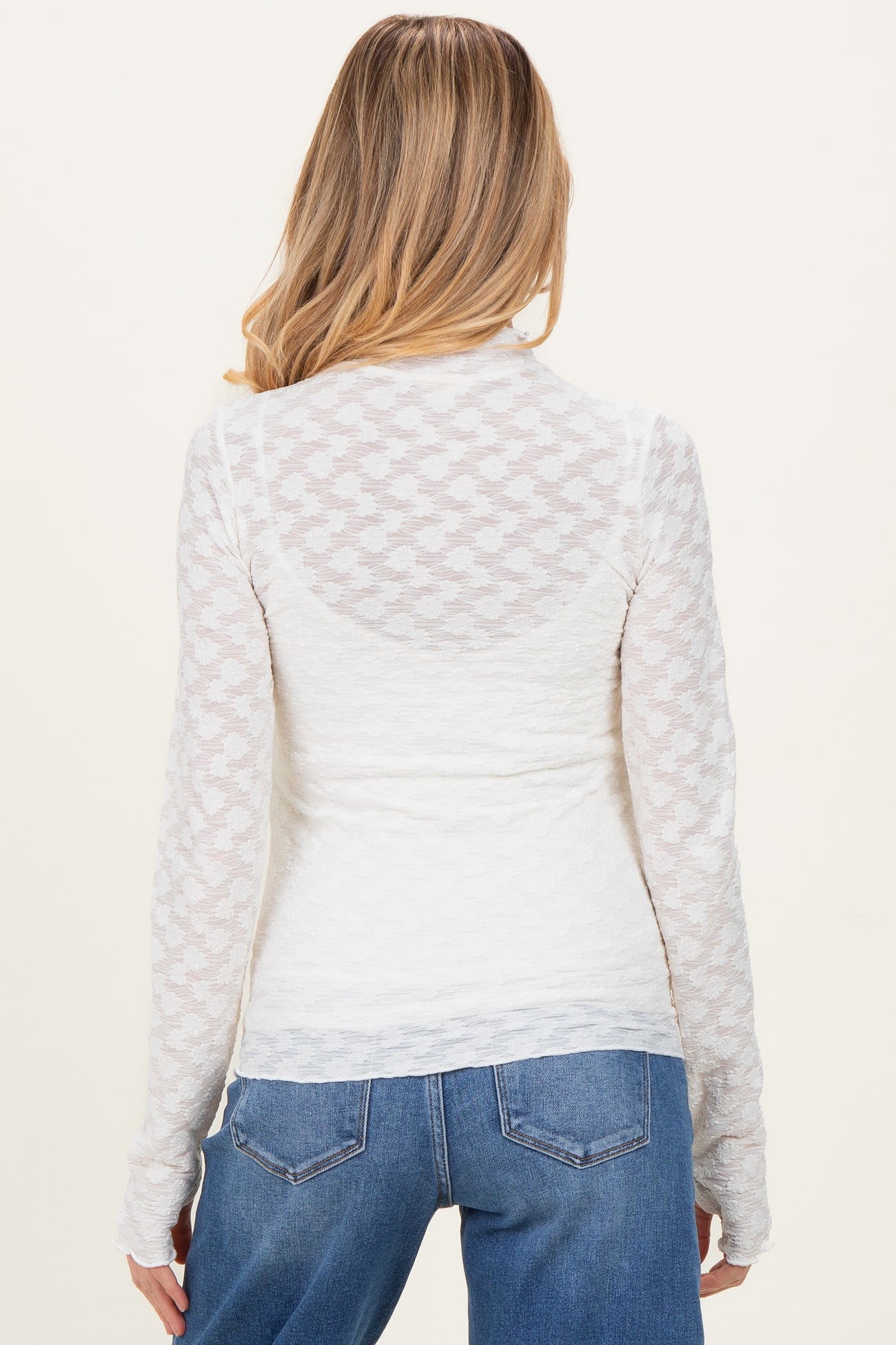 woman wearing a white long sleeve maternity top with textured details and a fitted style, showing the back view