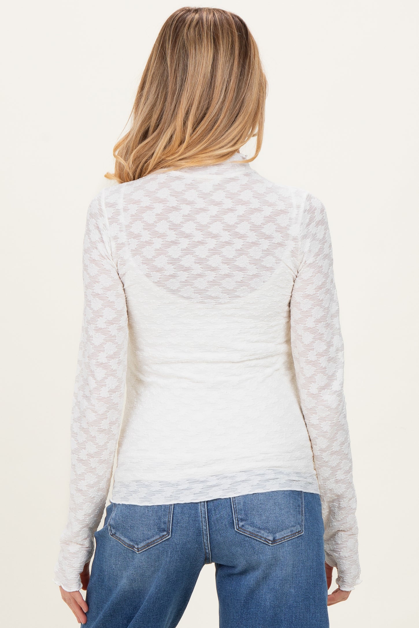 woman wearing a white long sleeve maternity top with textured details and a fitted style, showing the back view