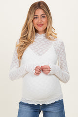 woman wearing a white lace maternity top with long sleeves and a scalloped neckline, styled with denim jeans