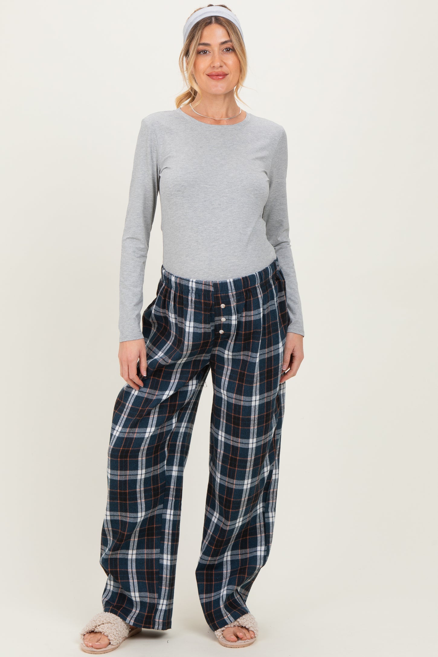 woman wearing a grey long sleeve maternity top and relaxed fit plaid maternity pajama pants with a headband
