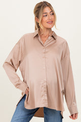 woman wearing a beige maternity button-up shirt with a relaxed fit and side slits, showing her baby bump