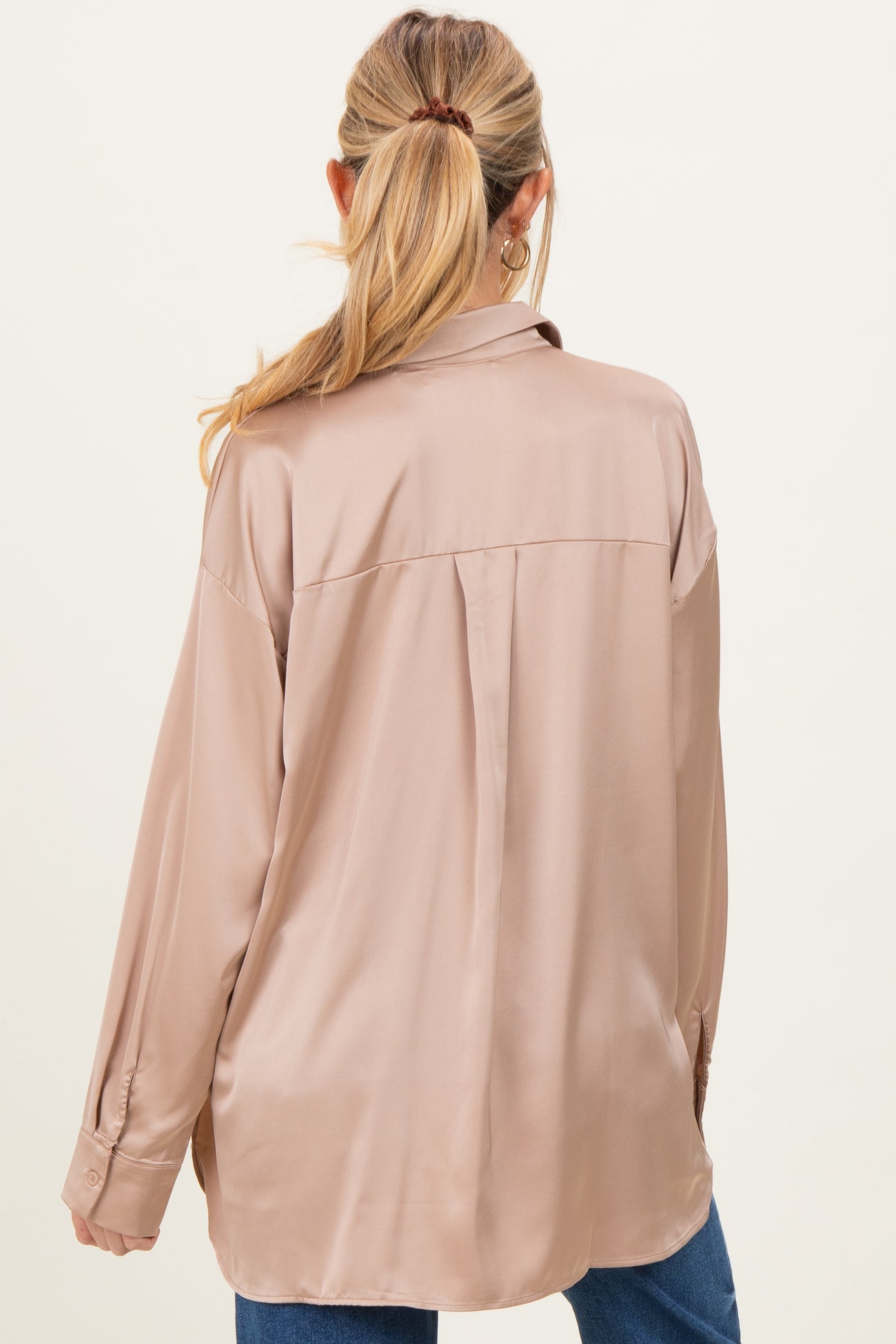 woman wearing a beige satin maternity shirt viewed from the back, featuring a relaxed fit and long sleeves