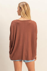 woman wearing a rust oversized long sleeve top with a relaxed fit and back seam detail, styled with denim shorts