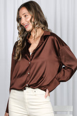 woman wearing a brown satin button-up shirt with a relaxed fit and rolled-up sleeves