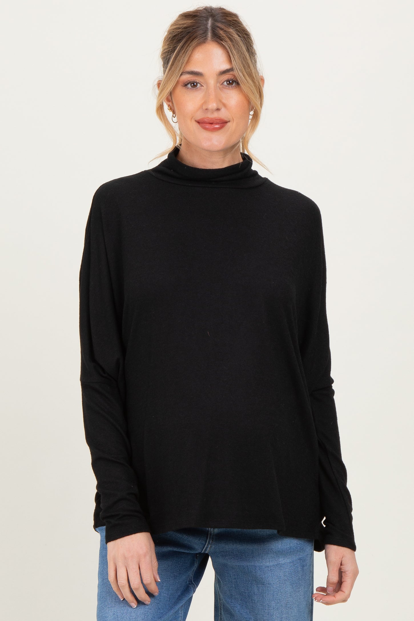 woman wearing a black maternity turtleneck sweater with long sleeves and a relaxed fit, baby bump visible