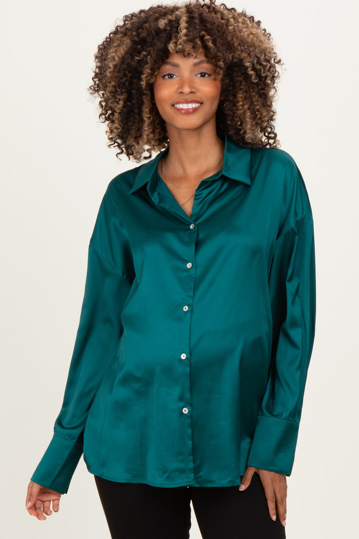 woman wearing a dark teal satin maternity shirt with a relaxed fit and button details, showcasing her baby bump