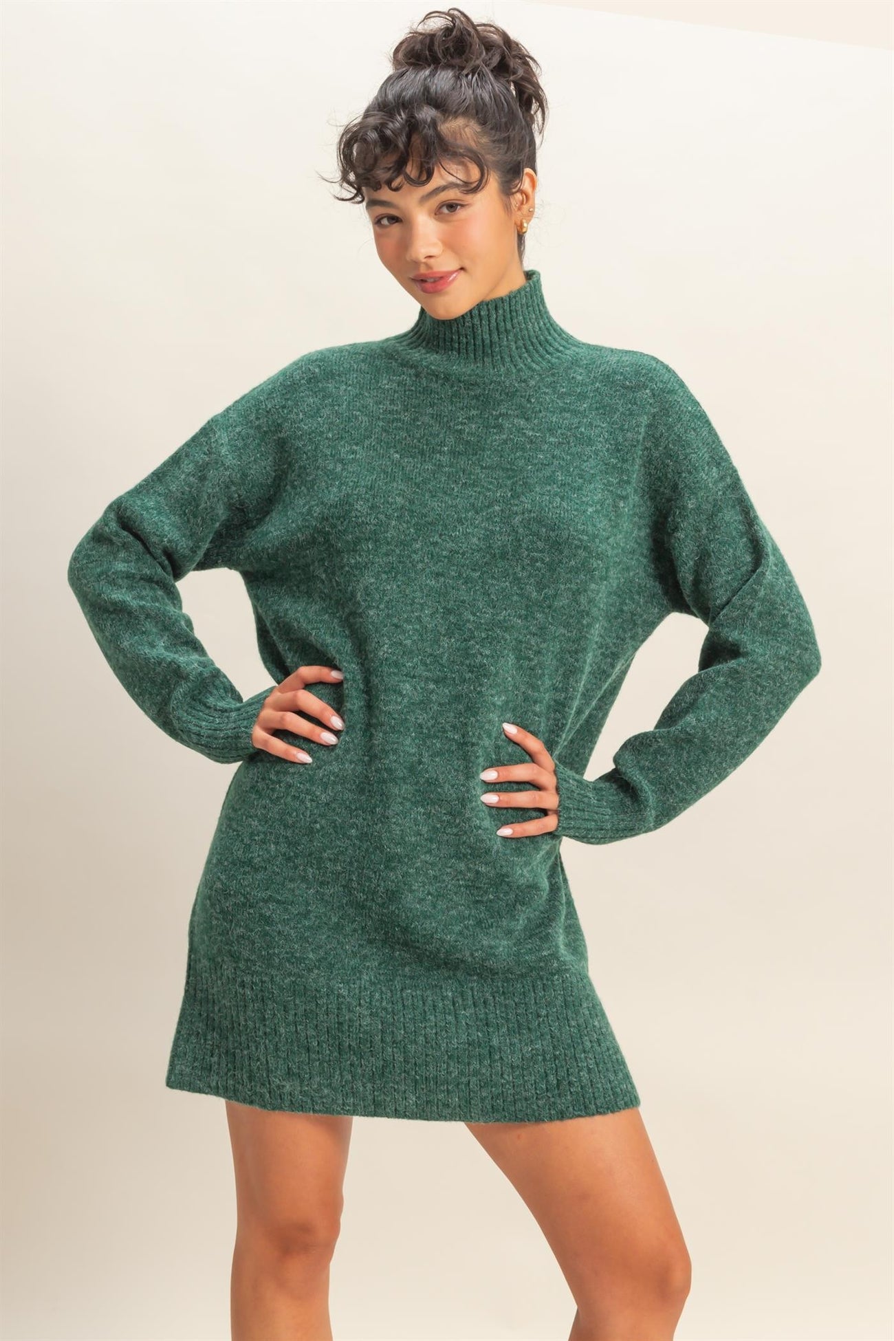 woman wearing a dark green oversized turtleneck sweater dress with long sleeves and a relaxed fit