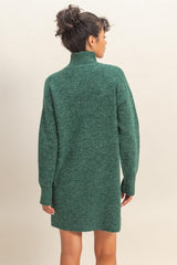 woman wearing a green oversized sweater dress with a high collar and long sleeves, viewed from the back
