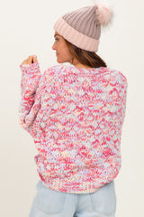 woman wearing a multicolor oversized knit sweater in pastel pink and blue with a soft pink beanie