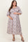woman wearing a floral print maternity dress with puff sleeves and a baby bump, standing and smiling