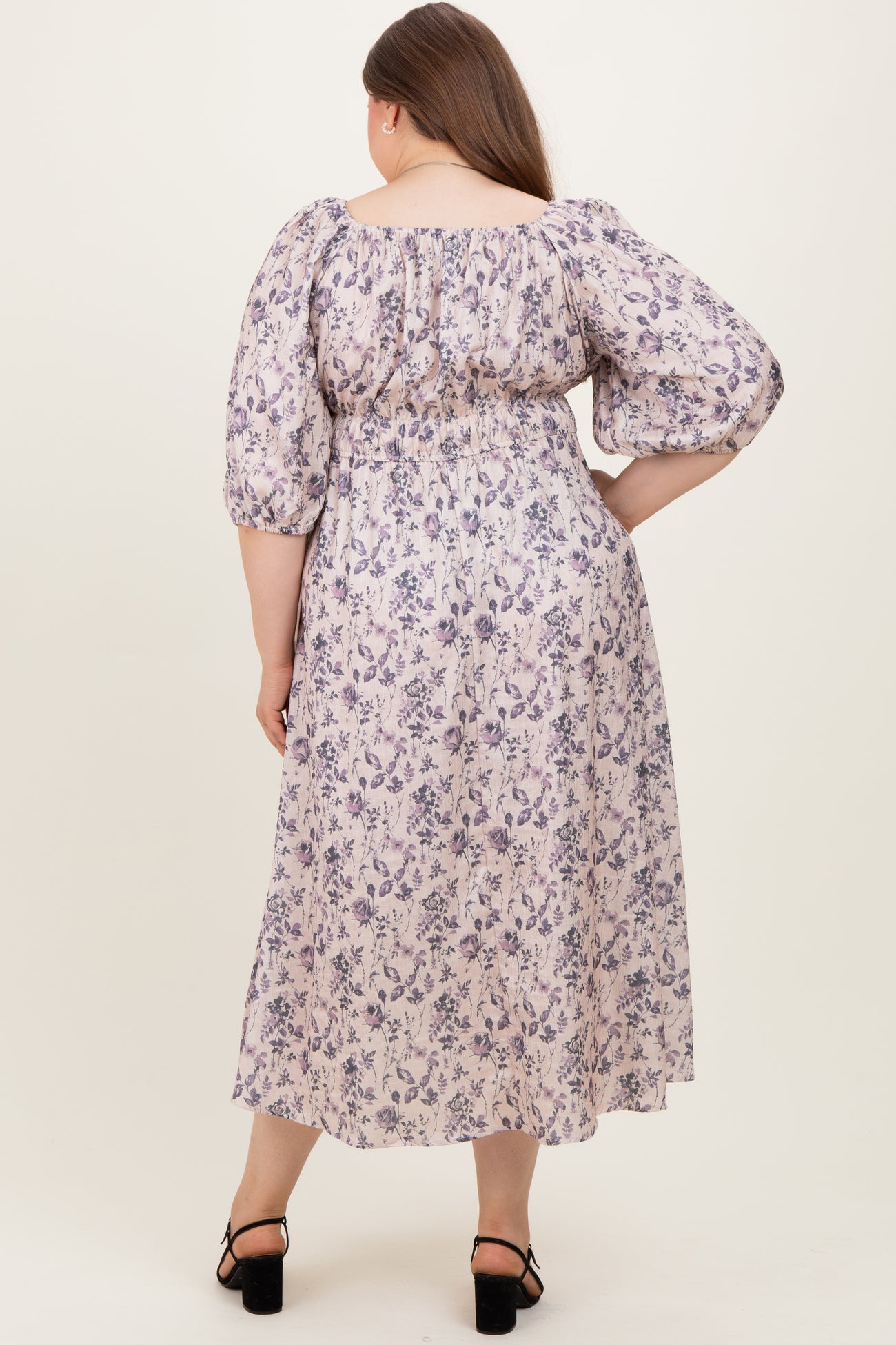 woman wearing a floral print maternity plus dress with puff sleeves and a gathered waist, showing her baby bump