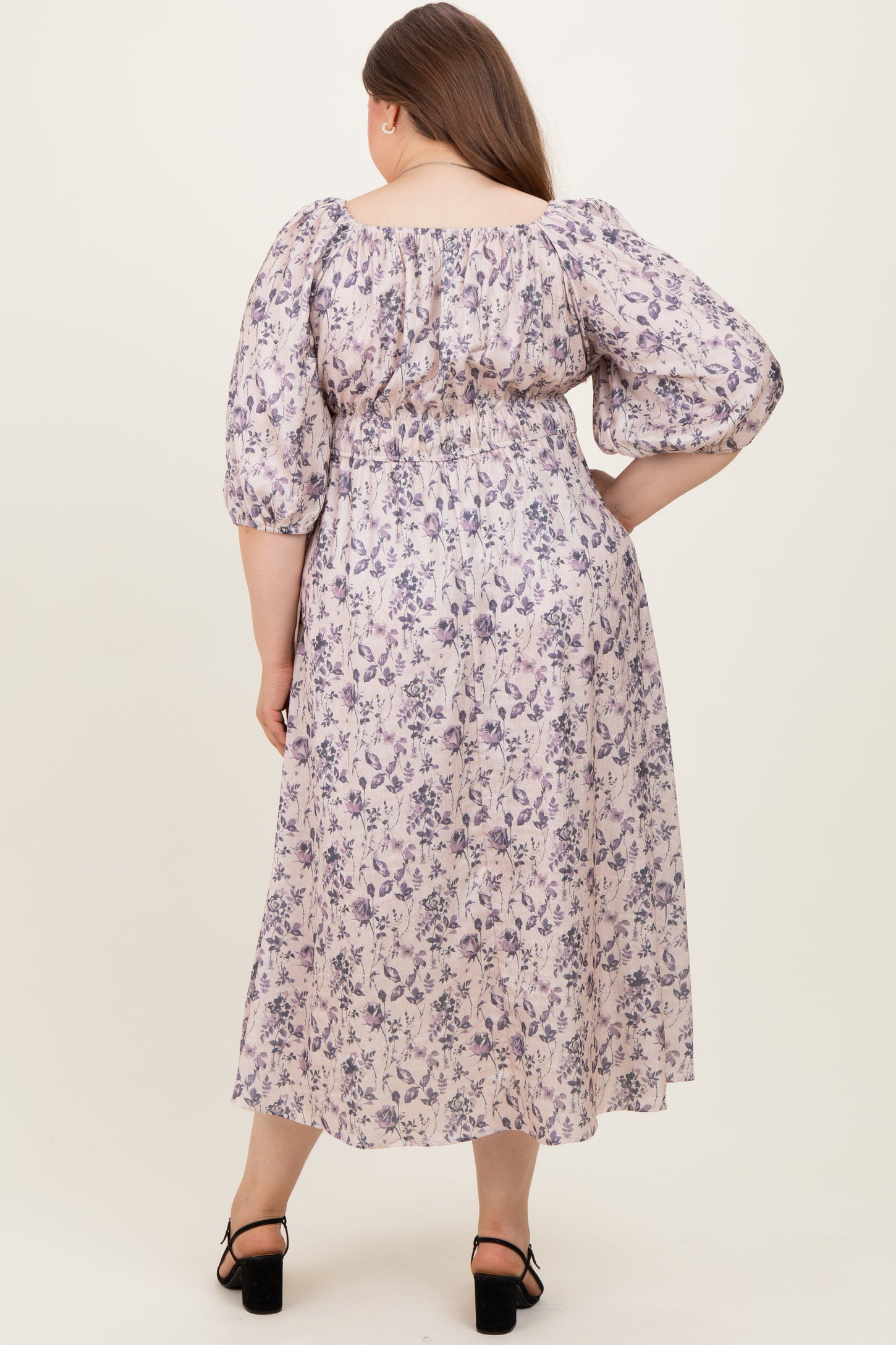 woman wearing a floral print maternity plus dress with puff sleeves and a gathered waist, showing her baby bump