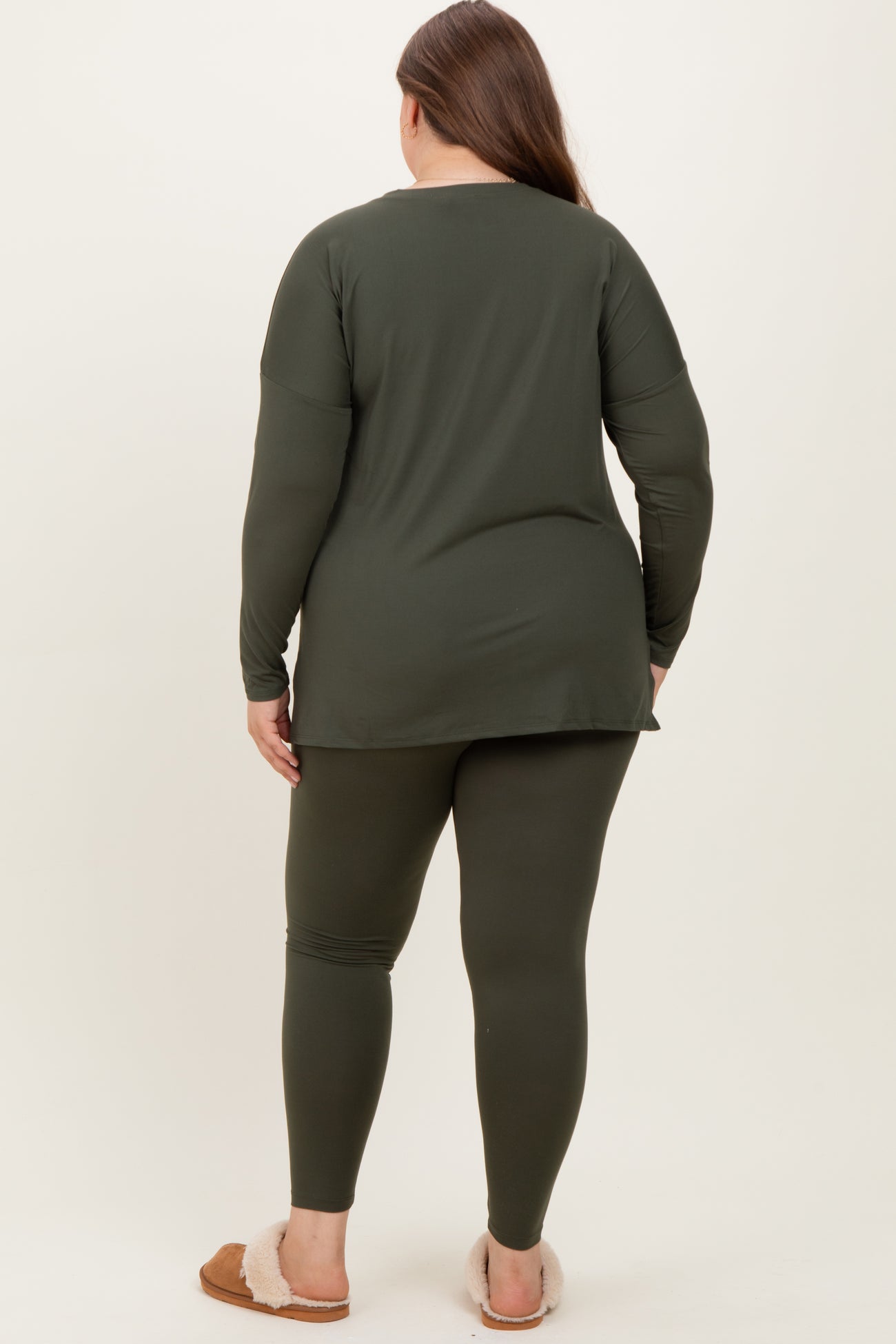 woman wearing an olive green maternity plus long sleeve top and matching leggings, showing a visible baby bump from behind