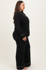 woman wearing a black plus size pajama set with white piping details, standing sideways