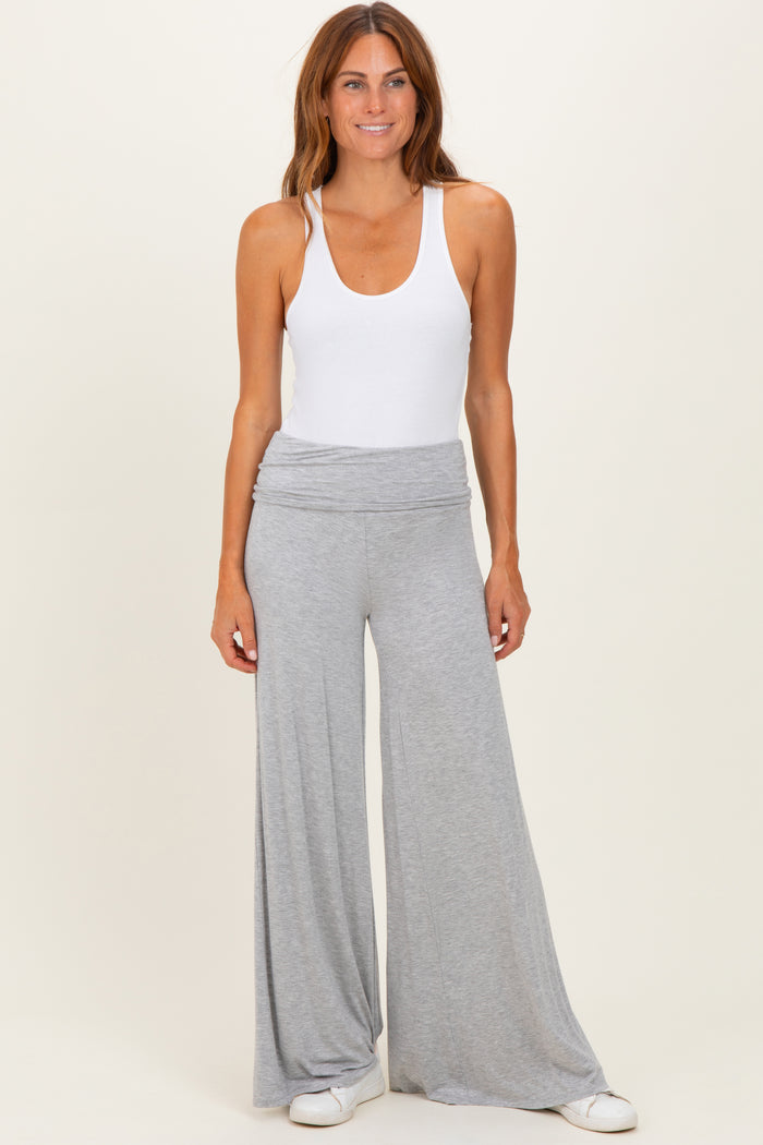 woman wearing a white tank top and light grey wide-leg pants, standing against a neutral background