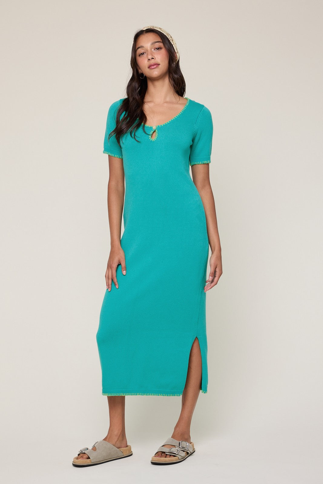 woman wearing a teal ribbed midi dress with a keyhole detail and side slit, paired with slide sandals