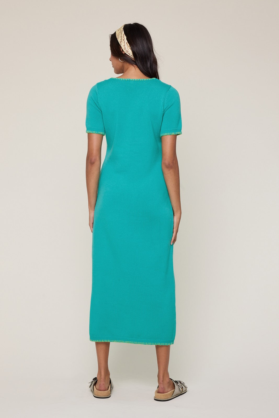 woman wearing a turquoise short sleeve knit maxi dress with contrasting trim, seen from the back