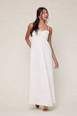 woman wearing a white maxi dress with spaghetti straps and a tie detail at the neckline