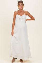 woman wearing a white maternity maxi dress with adjustable straps and a front tie, showcasing her baby bump