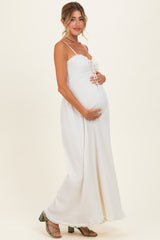 woman wearing a white maternity maxi dress with adjustable straps and holding her baby bump