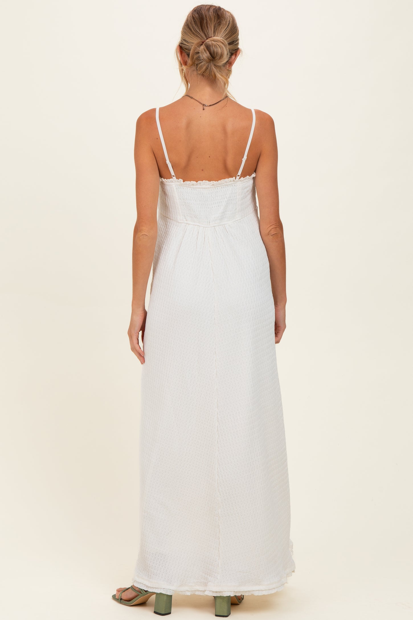 woman wearing a white maternity maxi dress with thin straps and a relaxed fit, showing a baby bump