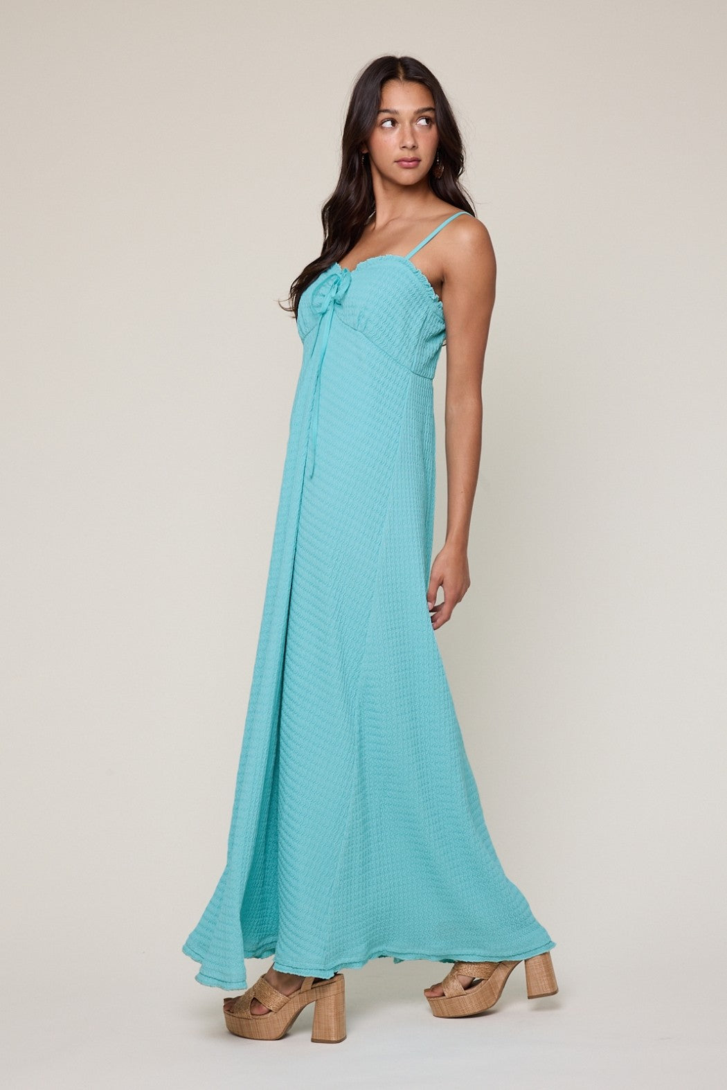 woman wearing a turquoise maxi dress with a tie front and spaghetti straps, paired with chunky platform heels