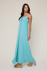 woman wearing a turquoise maxi dress with a tie front and spaghetti straps, paired with chunky platform heels