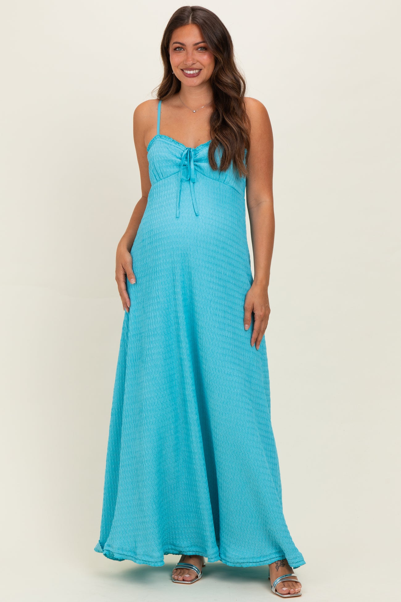 woman wearing a turquoise maternity maxi dress with a tie detail and a visible baby bump