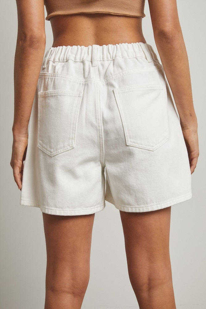 woman wearing white high-waisted denim shorts with an elastic waistband and back pockets
