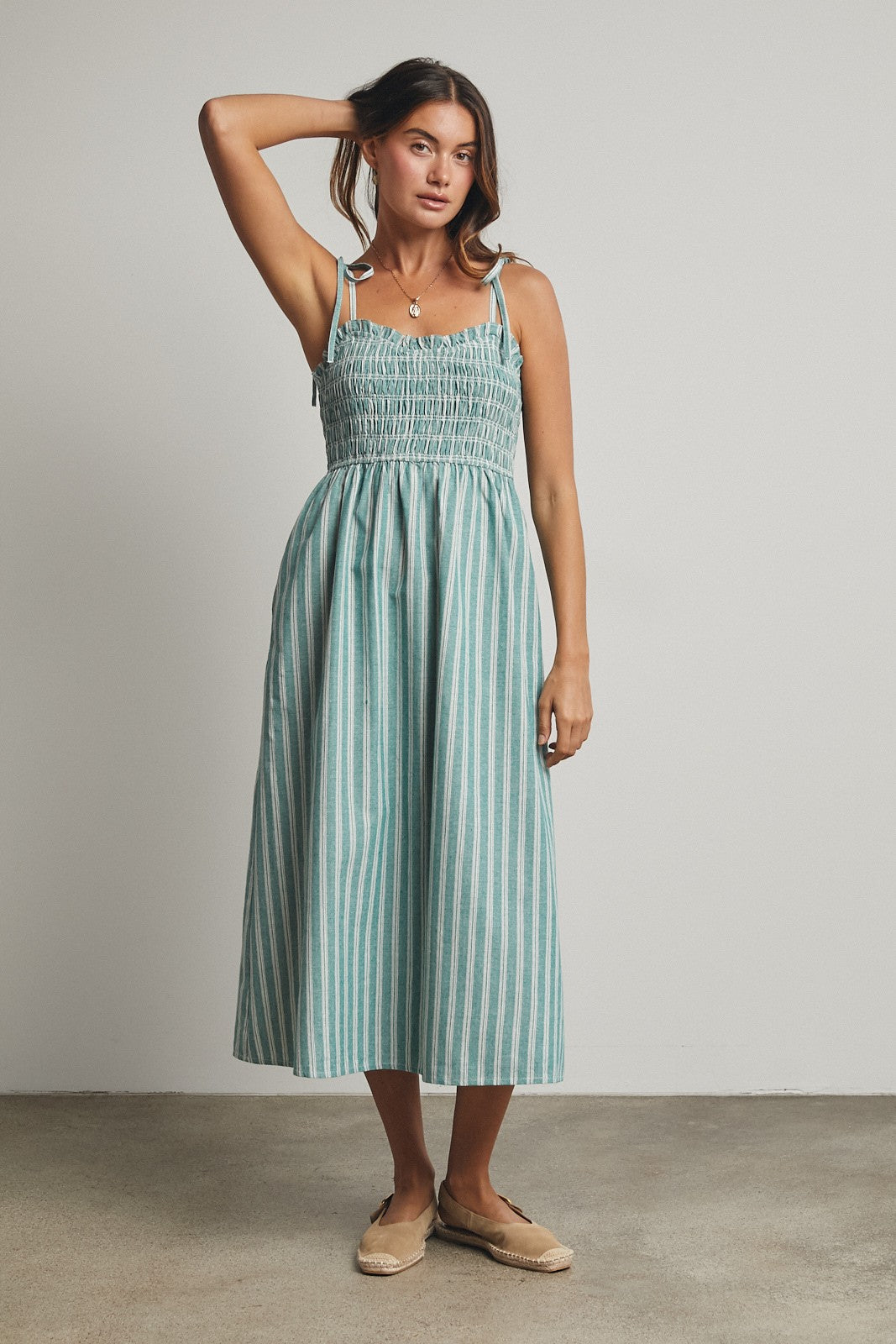 woman wearing a teal and white striped midi dress with smocked bodice and tie straps