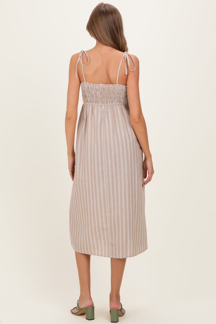 woman wearing a beige striped maternity dress with spaghetti straps and smocked back, showing a baby bump
