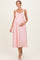 woman wearing a pink maternity dress with lace detailing, holding her baby bump, and walking gracefully