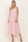 woman wearing a pink midi dress with lace trim and adjustable straps, standing on a neutral background